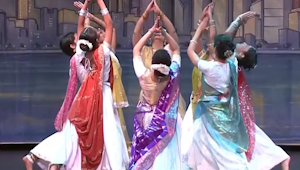 Indian classical dancers wearing colorful dresses on stage.