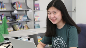 Summer reading volunteer sitting at the youth services summer reading table