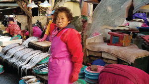An older Korean woman standing at a stall