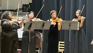 Four women performing on string instruments