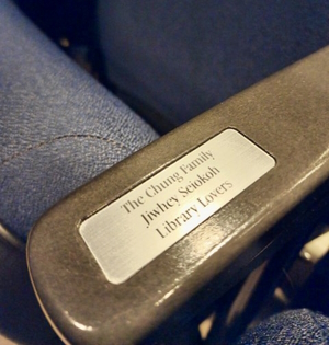 A photo of an auditorium seat with a commemorative plaque