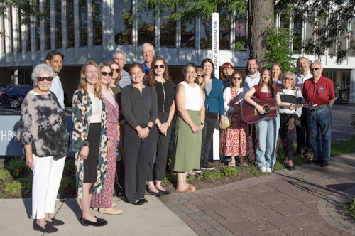 Several people stand outside the library for the Peace Pole dedication