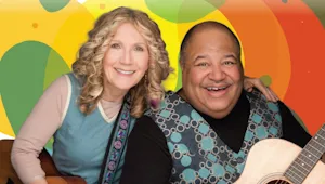 a woman with a man holding a guitar in front of a colorful background